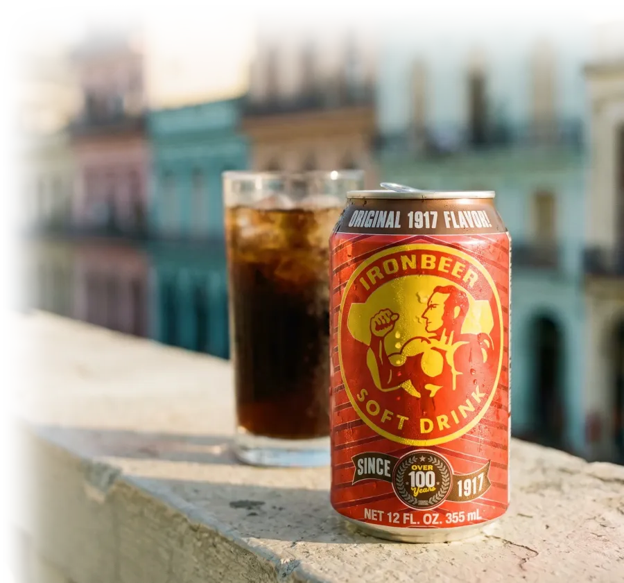 Ironbeer can and a glass of soda with ice on a stone ledge