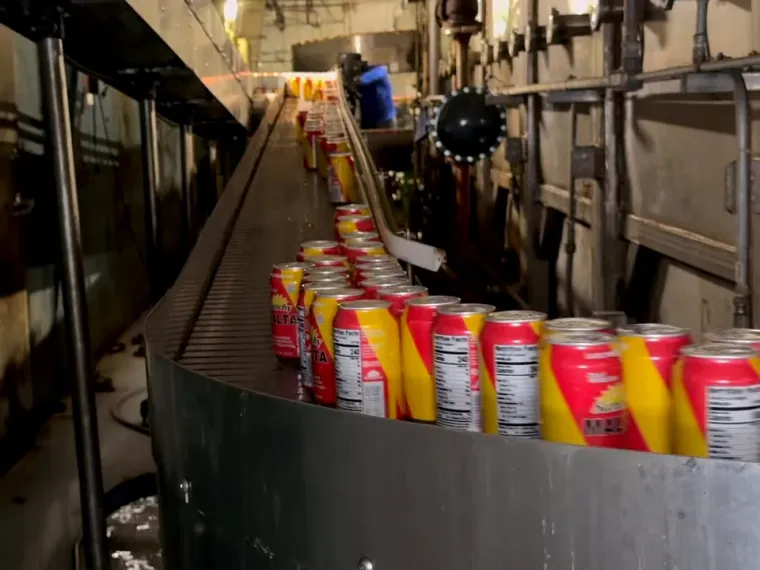 Sunchy Malta cans climbing an incline conveyor